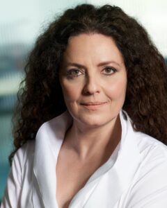 White Woman With Long Curly Dark Hair In A White Blouse With High Collar